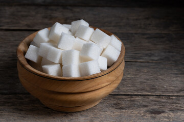 Refined sugar cubes in wooden cup.