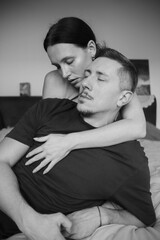 Sensual couple on the bed. A young and attractive man and woman kiss and hug, loving each other. Beautiful heterosexual couple of lovers