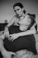 Sensual couple on the bed. A young and attractive man and woman kiss and hug, loving each other. Beautiful heterosexual couple of lovers