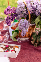 Still life with a basket of lilac flowers, glasses, wine, fruit and croissants. Beautiful picnic close-up picture