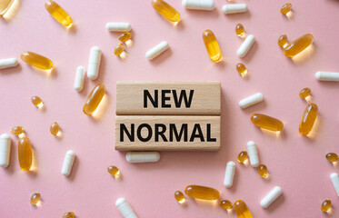 New normal symbol. Wooden blocks with words New normal. Beautiful pink background with pills....