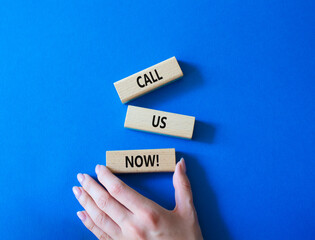 Call us now symbol. Wooden blocks with words Call us now. Beautiful blue background. Businessman hand. Business and Call us now concept. Copy space.