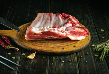 Raw lamb ribs on a cutting board before slicing and cooking. Work environment on a vintage kitchen table with spices and meat. Asian cuisine.