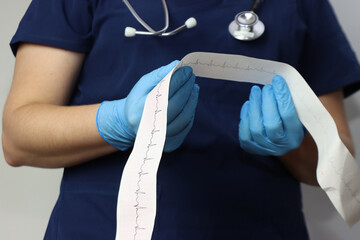 Health care professional wearing surgical scrubs, gloves and with a stethoscope in the neck looking...