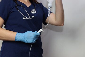 Health care professional wearing gloves holding and IV drip in the hands with a stethoscope in the...