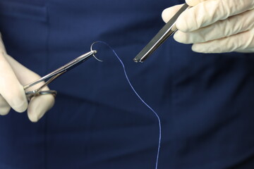 Close up in a surgical need beeing hold by a surgical equipment by a professional wearing sterile...