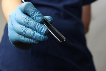 Professional wearing gloves holding a surgical instrument with close up