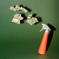 Spray bottle and dollars creative concept of business, economy or social issues. Green background...