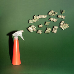 Spray bottle and dollars creative concept of business, economy or social issues. Green background...
