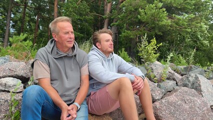 son and father sitting in nature and talking, family concept, spending time together, different generations