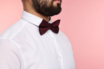 Man in shirt and bow tie on pink background, closeup