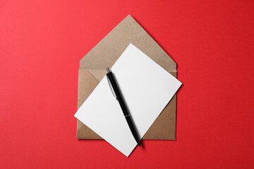 Blank sheet of paper, letter envelope and pen on red background, top view
