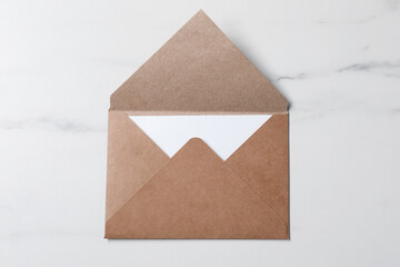 Letter envelope with card on white marble table, top view