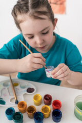 Cute little girl mixing paints on palette. Selected Focus