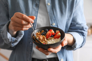 Woman eating tasty granola with berries, yogurt and seeds, closeup