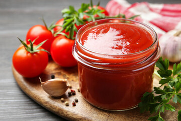 Tasty ketchup, fresh tomatoes, parsley and spices on grey wooden table