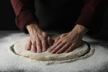 Woman kneading pizza dough at table, closeup