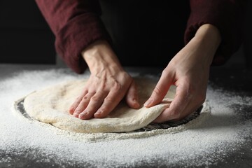 Woman kneading pizza dough at table, closeup
