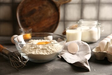 Making dough. Flour with egg yolk in bowl and whisk on grey textured table, closeup
