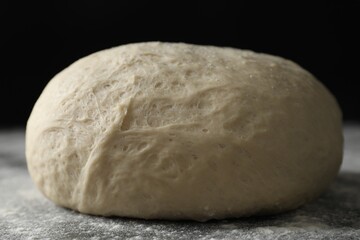 Raw homemade dough and flour on black table, closeup