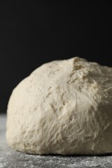 Raw homemade dough and flour on black table, closeup
