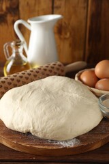 Raw dough, rolling pin and ingredients on wooden table