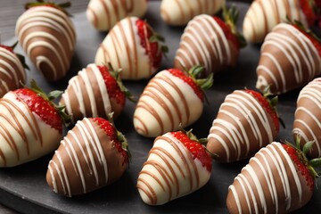 Delicious chocolate covered strawberries on black board, closeup
