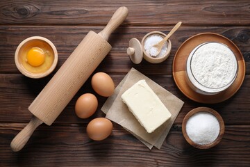 Making shortcrust pastry. Rolling pin and different ingredients for dough on wooden table, flat lay