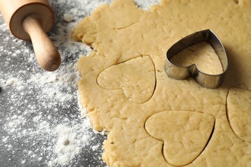 Making shortcrust pastry. Raw dough, flour, cookie cutter and rolling pin on grey table