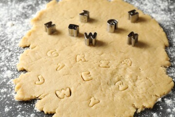 Making shortcrust pastry. Raw dough and cookie cutters on grey table