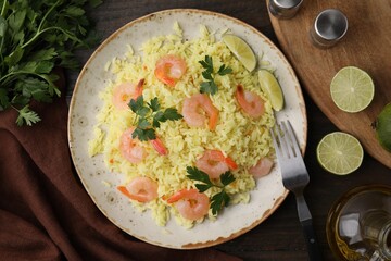 Delicious risotto with shrimps, lime and parsley served on wooden table, flat lay