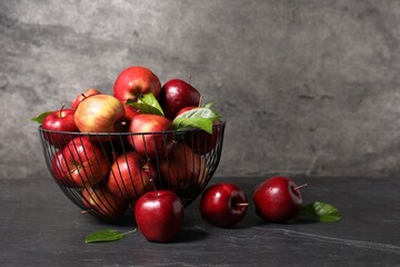 Fresh red apples and leaves on dark grey table. Space for text