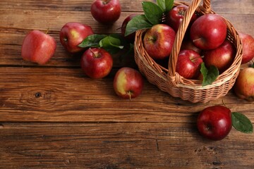 Fresh ripe red apples and leaves on wooden table. Space for text