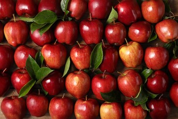 Fresh ripe apples with leaves on wooden table, flat lay