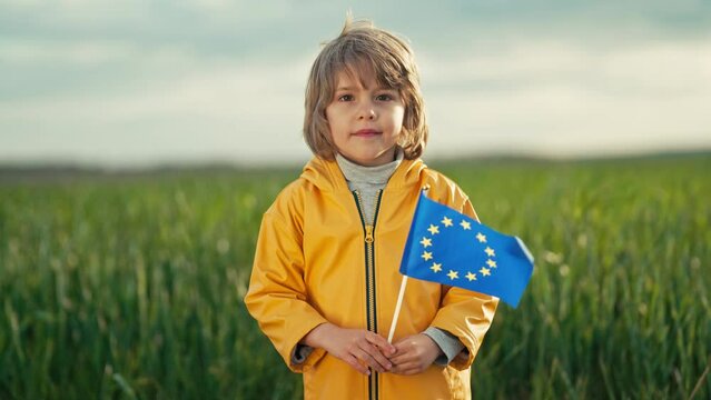 Little cute boy with European union flag in field. Happy child, kid smiling, EU