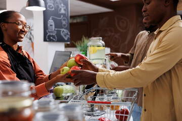 African American owner helps customers at eco friendly store with fresh organic products. Selective...