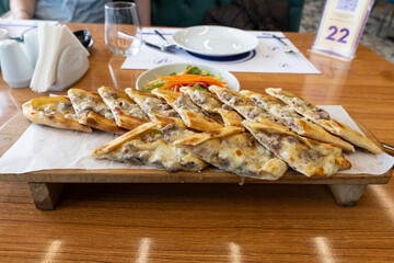 Turkish pita with minced meat. Turkish pizza with minced meat pide and a bowl of salad on a brown...