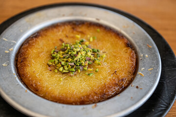 Delicious traditional Turkish kunefe with pistachio on it. Served hot and with syrup. Turkish Künefe, Hot and Cheesy Southeastern Dessert.