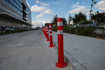 Orange traffic cone, parking is prohibited. Plastic red barrier. Row of red and white traffic barrier pole on road. A barrier made of plastic columns with reflective pigment on an asphalt road. 