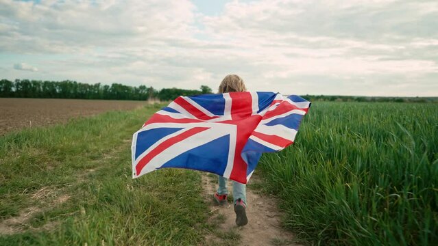 Little boy british patriot kid running with national flag on countryside road.