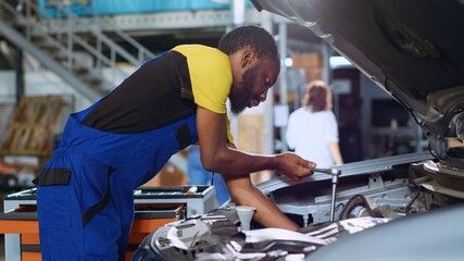 Experienced technician in car service uses torque wrench to tighten studs inside vehicle after...