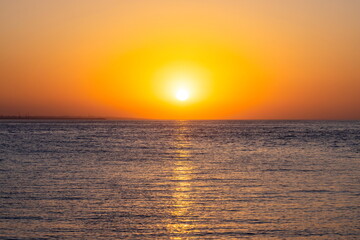 Fototapeta premium Sole al tramonto con riflessi dorati sul mare