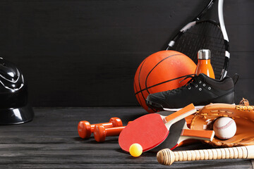 Many different sports equipment on dark grey wooden table