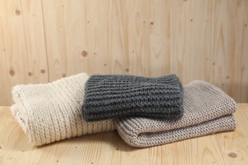 Stylish soft knitted scarfs on wooden table