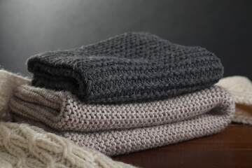 Knitted scarfs on wooden table against gray background, closeup