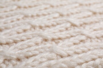 Beige knitted scarf as background, closeup view