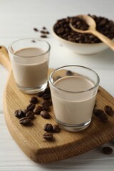 Coffee cream liqueur in glasses and beans on white wooden table