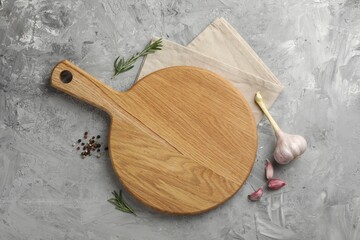 Cutting board, garlic, spices and rosemary on grey textured table, flat lay. Space for text