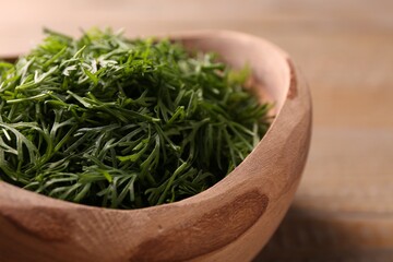 Fresh cut dill in wooden bowl on table, closeup