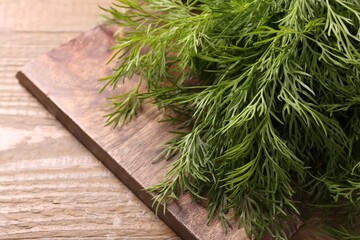 Board with sprigs of fresh dill on wooden table, closeup